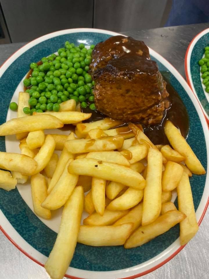 A plate of pub food with chips and peas