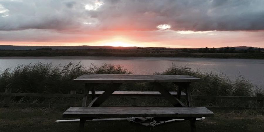 A picnic bench beside the river at sunset